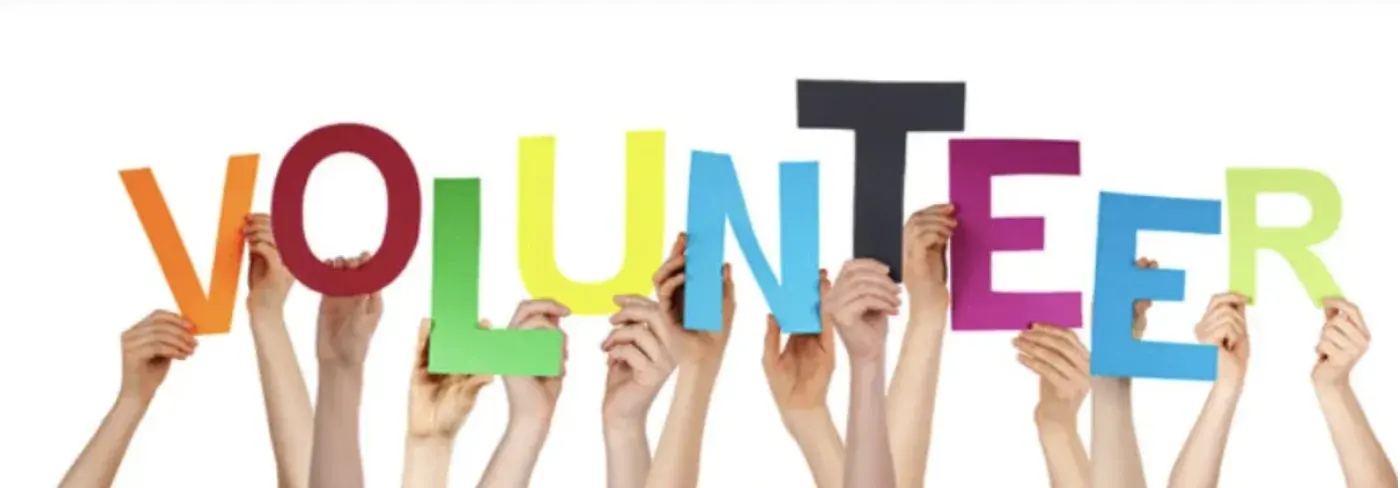 Raised hands hold up colorful letters that spell volunteer.